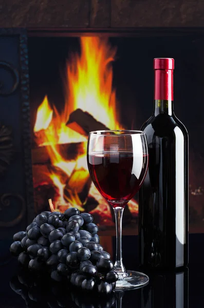 Bottle of wine and glass of wine on the background of the firepl — Stock Photo, Image