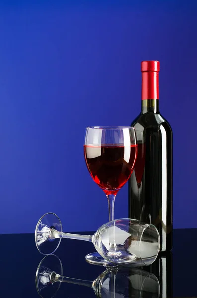 Glasses and bottle of wine on bright color background — Stock Photo, Image