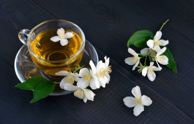 Yasemin çiçekli güzel kokulu çay ve koyu ahşap arka planda bir bardak çay. Üst görünüm.