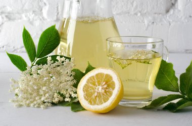 Beyaz masada dilimlenmiş limonlu taze mürver çiçeği içeceği. Yakın plan..