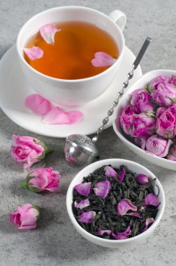 Gri desenli bir masada yapraklar ve gül tomurcuklarıyla çay. Üst Manzara. Yakın plan..