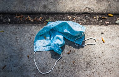 Asfaltta kullanılmış bir tıbbi maske var. Karantina sona erdi. Hareket özgürlüğü ve dayanıklılık