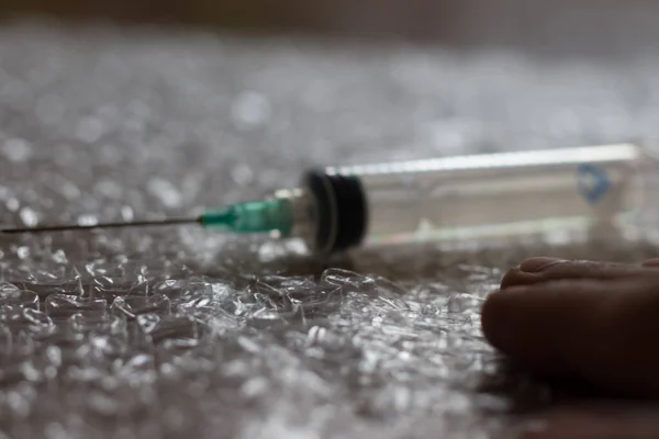 注射器 针头和人类的手放在有粉刺的聚乙烯上 病毒疫苗 — 图库照片