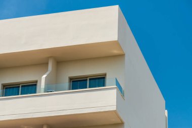 Yazın mavi gökyüzüne karşı açık balkonları olan modern yeni bina.