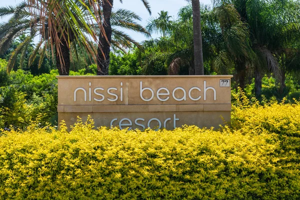 Agia Napa, Kıbrıs - 26 Mayıs 2019: Nissi Beach Resort Hotel tabelası, Ayia Napa. Bu işaret palmiye ağaçlarının arka planında çalılıklara asılmış..