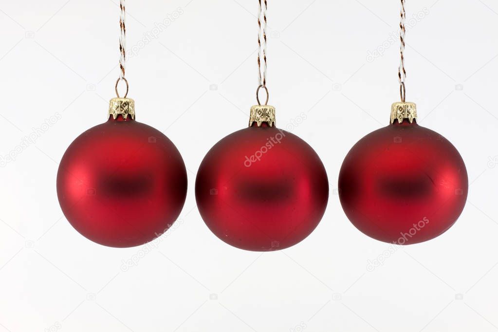 Three red Christmas balls photographed on a white background