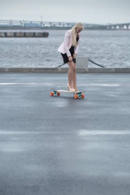 Güzel genç kız onun longboard th yakınındaki yolda sürme