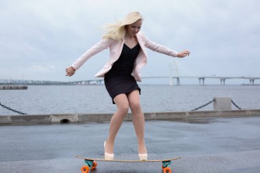 Güzel genç kız onun longboard th yakınındaki yolda sürme