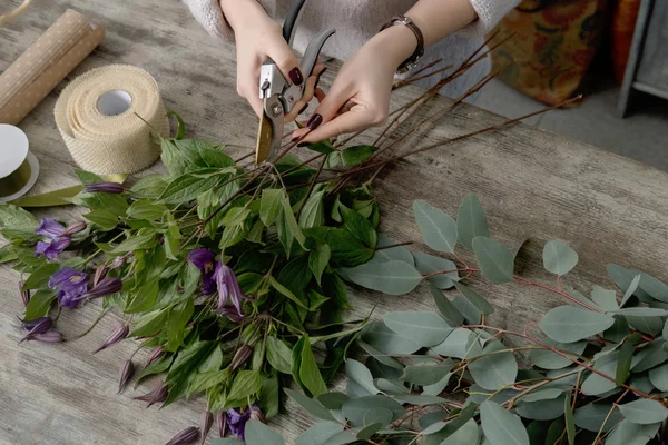 Las manos de florista contra escritorio con herramientas de trabajo y costilla — Foto de stock gratis