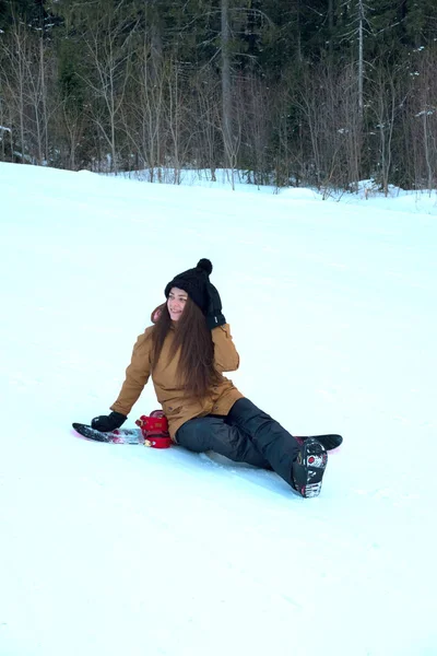 Linda chica con una tabla de snowboard en la estación de esquí —  Fotos de Stock