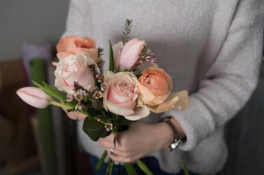 Çiçekçi kız bir buket çiçek paketliyor.