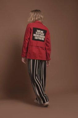 Genç kız moda giysiler bej renkli bir arka plan üzerinde poz. 