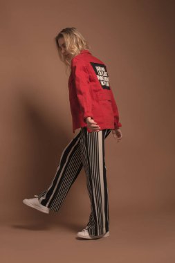 Genç kız moda giysiler bej renkli bir arka plan üzerinde poz. 