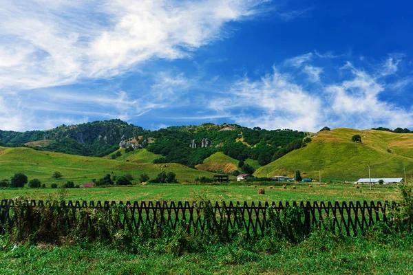 Велика ферма біля підніжжя зелених пагорбів — стокове фото