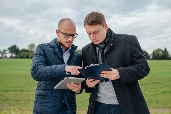 Two young investors are having a business meeting outside. Garde