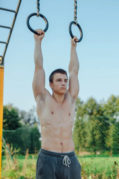 El hombre está parando en la barra. Fondo de gimnasio al aire libre Fotos De Stock Sin Royalties Gratis