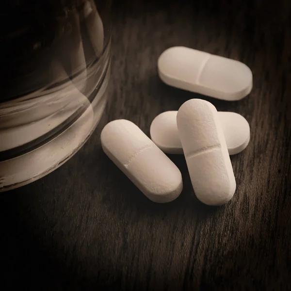 Tablets and a glass of water — Stock Photo, Image