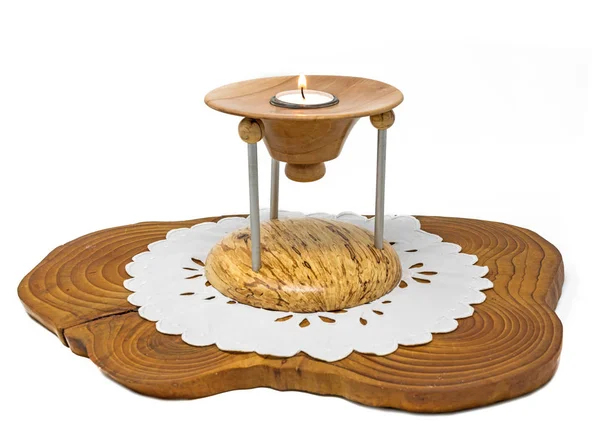 Wieloczęściowy drewniany świecznik z palącą się świecą stoi na ciemnej drewnianej desce — Zdjęcie stockowe