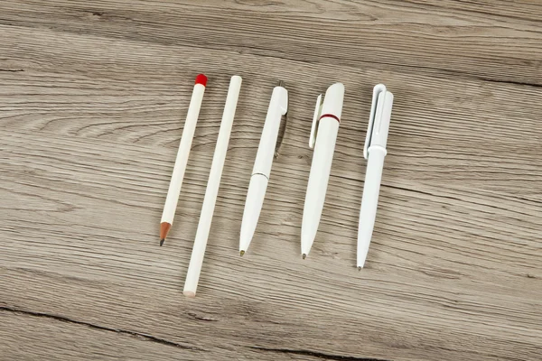 Set of pens and pencils on a wooden background.