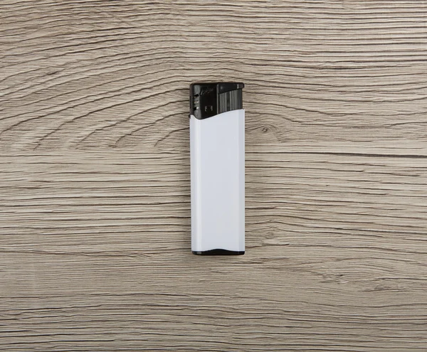 Briquet à gaz blanc et noir sur fond bois . — Photo