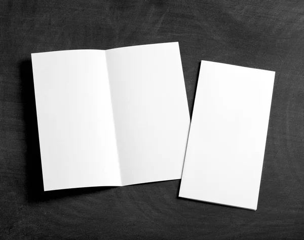 Folheto de papel dobrável branco em branco em um quadro preto — Fotografia de Stock