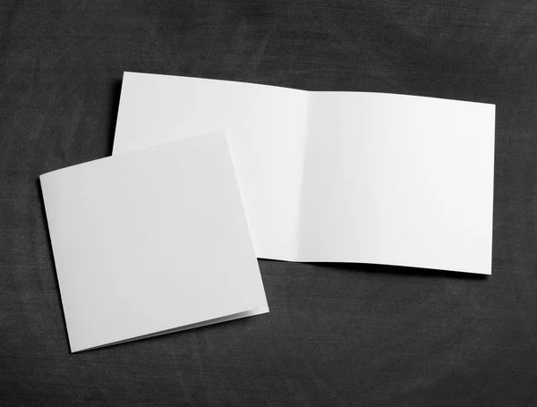 Folleto de papel plegable blanco en blanco sobre una pizarra negra —  Fotos de Stock