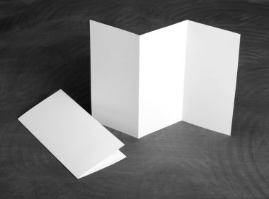 Boş beyaz kağıt el ilanı siyah bir kara tahta katlama