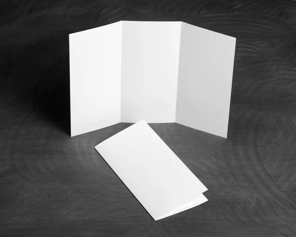 Blank white folding paper flyer on a black chalkboard — Stock Photo, Image