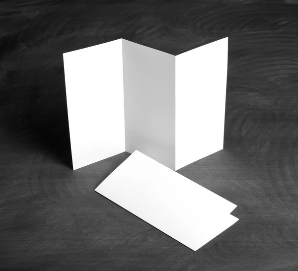 Λευκό κενό πτυσσόμενα flyer χαρτί σε ένα μαύρο πίνακα κιμωλίας — Φωτογραφία Αρχείου