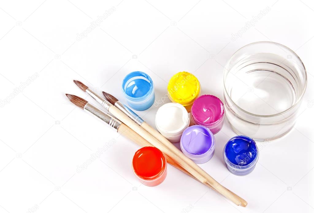 Jars with gouache and paint brushes on a white background.