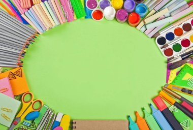 Okul malzemeleri çerçeve yeşil bir arka plan üzerinde.