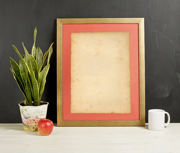 Bitki pot, kupa ve elma wo üzerinde boş fotoğraf çerçevesi alay et