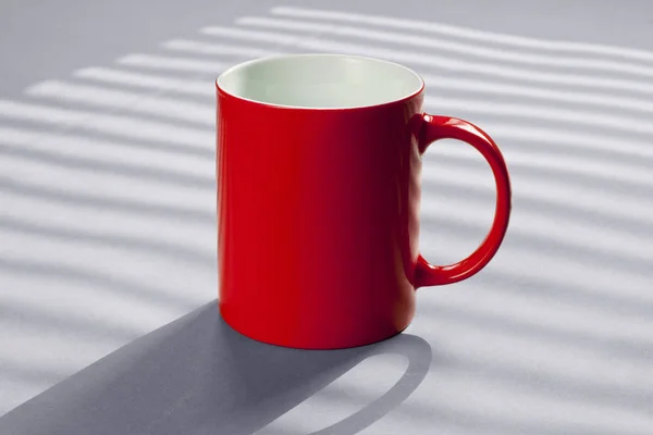 Caneca vermelha em pé sobre uma mesa cinza . — Fotografia de Stock