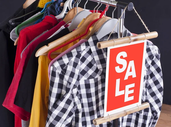 Venda em uma loja de roupas - sinal de desconto em um rack de roupas . — Fotografia de Stock