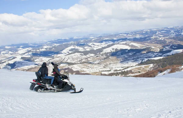 Men's and women riding snowmobile at winter Carpathian. — Stock Photo, Image