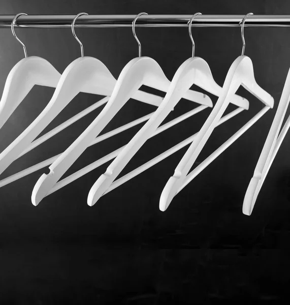 Wit houten kleding hanger op metalen dwarsbalk boven zwart. — Stockfoto