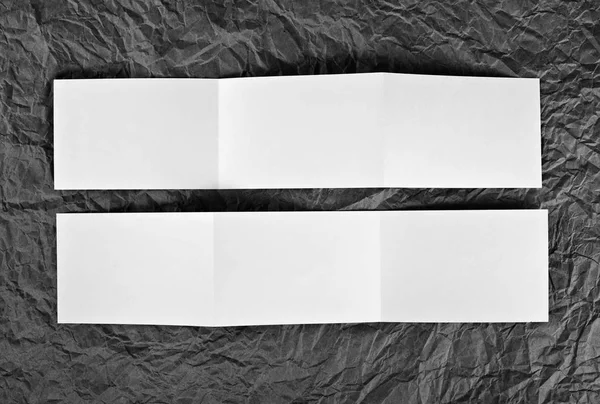 Folleto en zigzag en blanco sobre un fondo de papel arrugado gris . — Foto de Stock