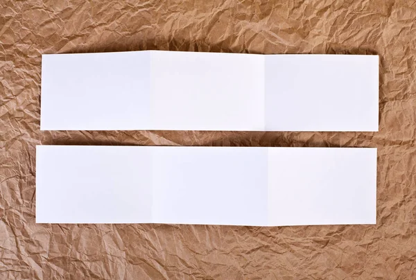 Leerer Zickzack-Flyer vor braunem faltigem Papierhintergrund. — Stockfoto