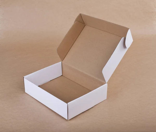 Witte kartonnen doos voor verpakking op een beige achtergrond geopend. — Stockfoto