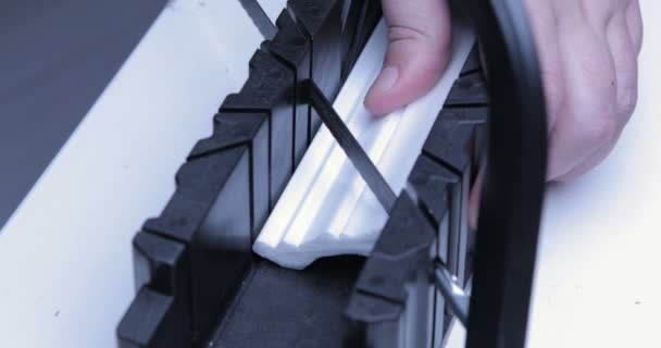 Man cuts plinth with special equipment. Holding device helps to hold white blanch, clips unnecessary parts with — Stock Footage Man Cuts Plinth Special Equipment Holding Device Helps Hold White Royalty Free Stock Video