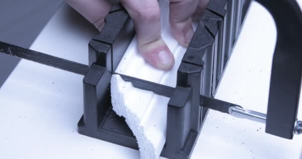 Man cuts plinth with special equipment. Holding device helps to hold white blanch, clips unnecessary parts with — Stock Footage Man Cuts Plinth Special Equipment Holding Device Helps Hold White Stock Video