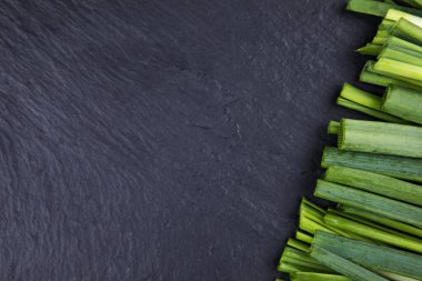 Siyah masadaki yeşil soğanlar, üst görünüm ve boşluk kopyala