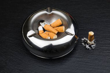 Stubbed cigarette butt stub with ash on black background