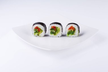 Arka planda beyaz kare bir tabakta üç suşi.. 