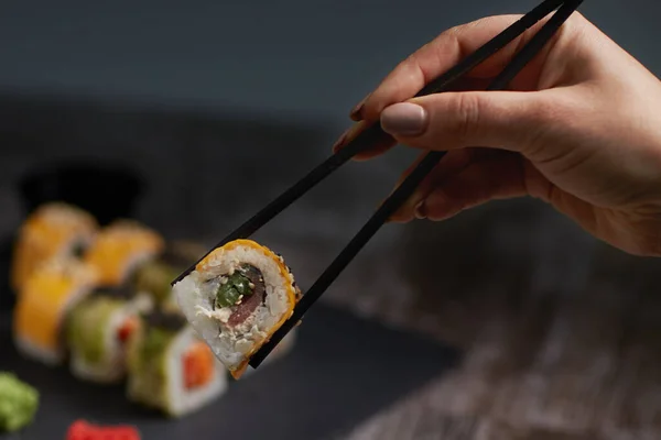 Pierwszym Planie Samica Trzyma Bułkę Sushi Pałeczkami Sushi Ustawione Kwadratowej — Zdjęcie stockowe