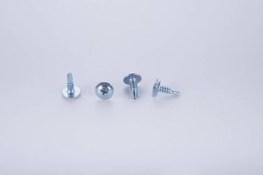 Beyaz arka planda büyük miktarlarda çelik vidalar