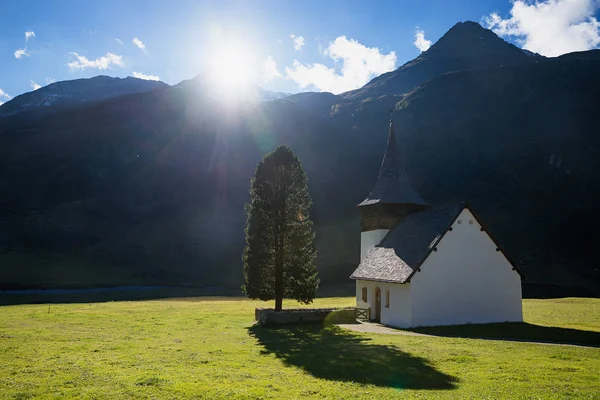 Petite chapelle de montagne et sapin haut, vallée ensoleillée — Photo