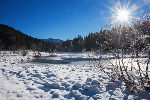 В горах снежный покров с небольшим ручейком и солнцем — стоковое фото