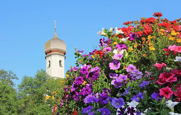 Kostelní věž a pestré letní květiny — Stock fotografie