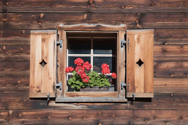 Farmstead window with wooden shutters and red geranium — Stock Photo, Image